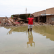 A man gestures as he wades through a flooded road in the town of Salmaniya, about 25 miles (35 km) southwest of the capital, Khartoum, Sudan, Thursday, Sept. 17, 2020.